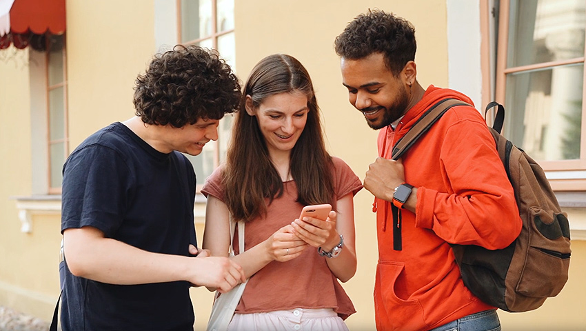 Drei junge Menschen spielen ein Outdoor-Handy-Game Drei junge Menschen spielen ein Outdoor-Handy-Game
